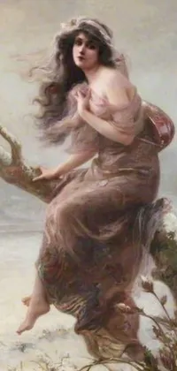 This phone live wallpaper features a beautiful painting of a female goddess sitting on a tree branch with her hair blowing and the winter mist around her