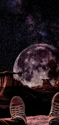 This stunning digital art phone live wallpaper features a breathtaking scene of a pair of feet resting on a rocky outcropping against a full moon backdrop