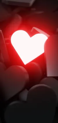 This stunning live wallpaper features a close-up shot of a red heart atop a pile of rocks, surrounded by scattered hearts and illuminated with red and white neon accents