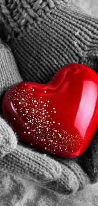 A stunning phone live wallpaper available for download now! Featuring a heart-shaped red ornament held in a pair of hands, this glittery and soft image makes the perfect addition to your phone screen