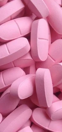 This phone live wallpaper showcases a pile of pink pills arranged neatly on a table