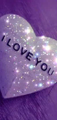 This live wallpaper features a heart-shaped stone with "I love you" etched into it on a romantic background with sparkles