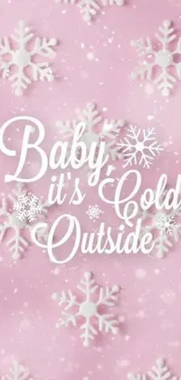 This exquisite phone live wallpaper showcases a charming pink background adorned with charming snowflakes and the words “Baby it's Cold Outside”