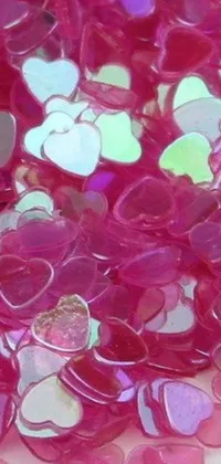This animated phone wallpaper is a lively pile of heart-shaped confetti sprinkled on top of a table covered with holographic plastic