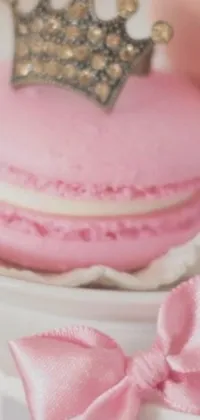 This cute live phone wallpaper showcases a pink macaron with a crown on top, highlighting its stunning texture and color