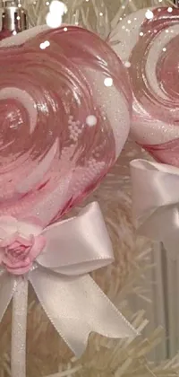This phone live wallpaper showcases two lollipops on a Christmas tree with striped red and white candy, translucent roses, rose gold heart, and glittery ornaments in an ivory background