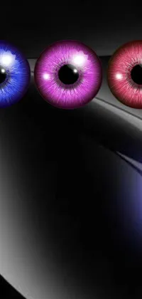 This live wallpaper for phones features a close-up of three sets of eyes in black, white, and purple