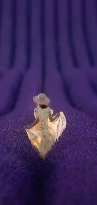 This stunning phone live wallpaper features a macro photograph of a white angel seated on top of a purple blanket