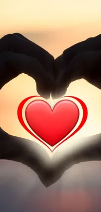 Looking for a romantic live wallpaper for your phone? Check out this stunning image of someone forming a heart shape with their hands