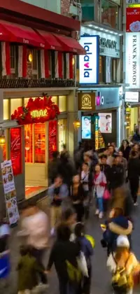 This live wallpaper features a bustling city street scene with a crowd of people walking down the street surrounded by tall buildings, European and Japanese architecture, warm street lights and a screenshot of a YouTube video
