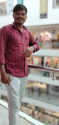 This phone live wallpaper features a hyperrealistic scene in a mall with a man standing next to a railing wearing an elegant red shirt contrasted with a maroon and white flannel pattern background