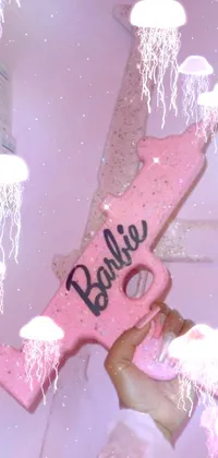 This phone live wallpaper features a close-up view of a toy gun held by an anime Barbie doll dressed in white against a graffiti background