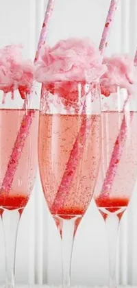 This phone live wallpaper features three glasses filled with pink cotton candy arranged on a table