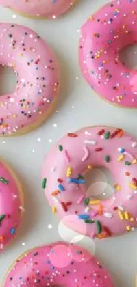 This live phone wallpaper features a cute and colorful design of a table full of pink donuts covered with sprinkles