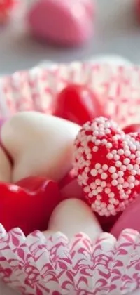 This bright and cheerful live wallpaper for your phone features a bowl overflowing with an array of delicious red and white candies, along with cute heart and picture accents