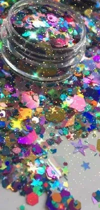 This phone live wallpaper features a glimmering jar of glitter, a microscopic photo, colorful rave makeup, and falling stars in a mesmerizing, hexagonal design