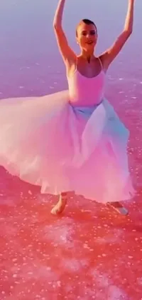 This live phone wallpaper showcases a striking colorized image of a woman in a pink dress, dancing gracefully in clear water surrounded by salt