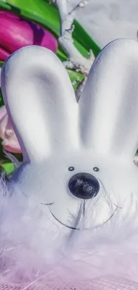 This phone live wallpaper features a charming white bunny mask set against a soft pink background adorned with delicate flowers and ethereal branches