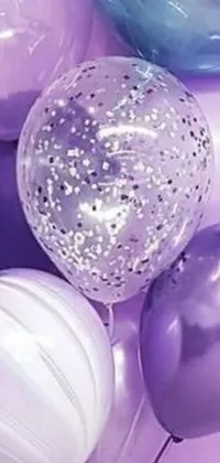 This delightful phone live wallpaper boasts an array of colorful balloons on a table with a picture on the wall in the background