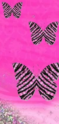 Looking for a chic and sophisticated phone wallpaper? Look no further than this stunning live wallpaper featuring three black and white butterflies against a soft pink background