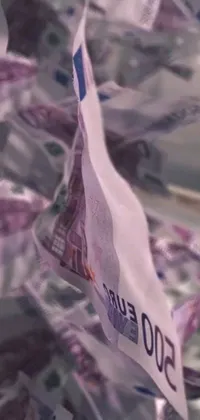 This live wallpaper boasts an image of a money pile on a table, with an interesting detail of ripped flag pieces