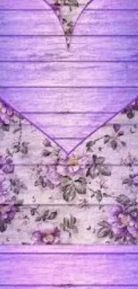 Get enchanted with this stunning phone live wallpaper featuring a breathtaking purple heart on a wooden table amidst an intricately designed art nouveau background of roses, clematis and other delicate flowers