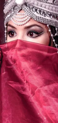 This enchanting phone live wallpaper showcases a mysterious woman with a red veil over her face and eyes, dressed in a flowing red gown and adorned with a sparkling diamond headband