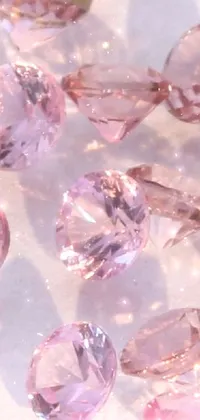 Decorate your phone screen with this stunning live wallpaper featuring a beautifully arranged bunch of pink diamonds sitting on a sleek table