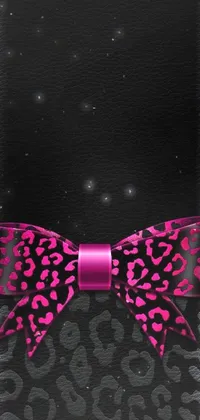 This phone live wallpaper features a mesmerizing close-up of a pink bow on a black background with shades of purple and pink in its leather garments