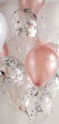 This lively phone live wallpaper features colorful balloons of various sizes and hues playfully bouncing off each other on a pretty light pink table