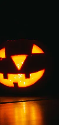 Get in the spooky spirit with our phone live wallpaper, featuring a lit-up jack o lantern in the dark