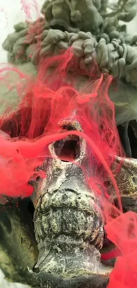 This phone live wallpaper features a mask with red hair by Louis Schanker in acid colored smoke, encompassing an elephant skull and displaying pink brains