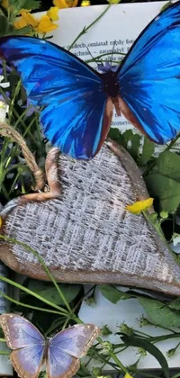 This exciting phone live wallpaper showcases a stunning blue butterfly resting on a book next to a beautiful folk art picture