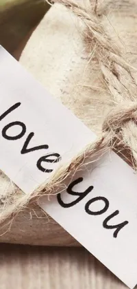 Enhance your phone’s beauty with this amazing and romantic live wallpaper! Beautifully crafted, this wallpaper features a loosely cropped burlap paper with the words "i love you" written on it in beautiful, loopy script