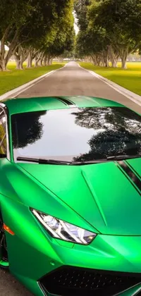 Looking for a thrilling phone wallpaper to showcase your love for fast cars? Check out this photorealistic live wallpaper featuring a vibrant green Lamborghini sports car parked next to the side of a road