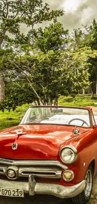 Enhance your phone with a captivating live wallpaper featuring a vintage red classic car parked on a rustic dirt road