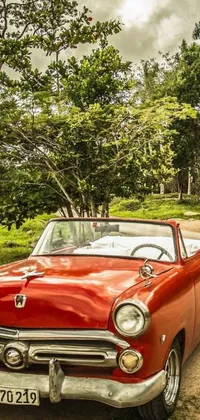 This live phone wallpaper depicts a red classic convertible car parked on a rustic dirt road in Jamaica