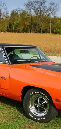 This live wallpaper features a striking orange muscle car parked on the side of a road