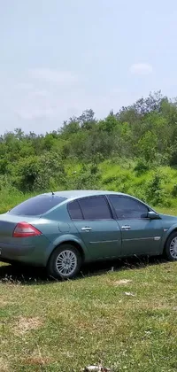This live phone wallpaper showcases a metalic green car parked peacefully in lush greenery
