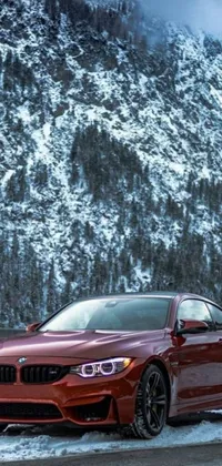 This live phone wallpaper showcases a red BMW parked in front of a breathtaking mountain landscape