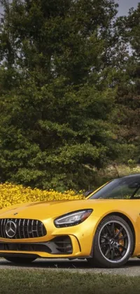 This stunning phone live wallpaper features a yellow Mercedes sports car parked on a road side surrounded by colorful flowers