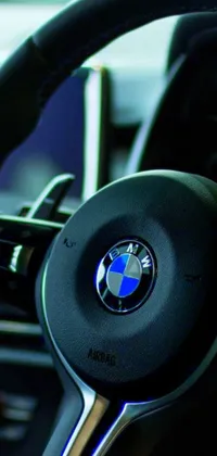 This phone live wallpaper showcases a digitally rendered, photorealistic close-up of a BMW steering wheel