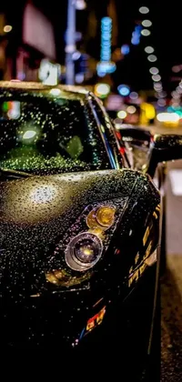 This phone live wallpaper is a stunning photorealistic image of a black sports car parked on the side of a wet road