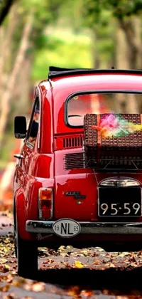 This live wallpaper features a classic red car driving down a tree-lined road with colorful fallen leaves