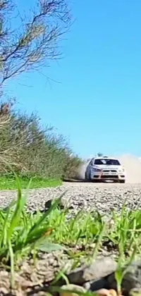 This live wallpaper showcases a rally car driving down a dusty road