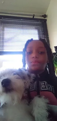 This phone live wallpaper features the close-up of a young African girl with light skin and black pigtails, taking a selfie while holding a small dog