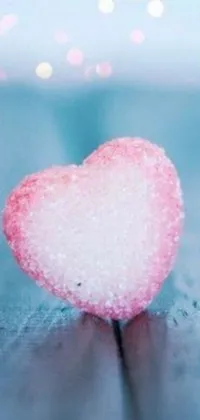 This mesmerizing live wallpaper depicts a charming pink heart resting atop a rustic wooden table against a backdrop of fluffy sugar snow
