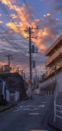 This live phone wallpaper displays a captivating scene of a busy street with lots of traffic, next to a tall building, set against a picturesque Japanese village silhouette in the backdrop of a cloudy sunset
