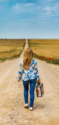 This live phone wallpaper features a beautiful girl walking down a dirt road with a suitcase and a picture