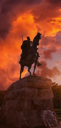 This live phone wallpaper displays a stunning statue depicting a rider on a horse against a bright red orange sky, with the city of Rome in the background
